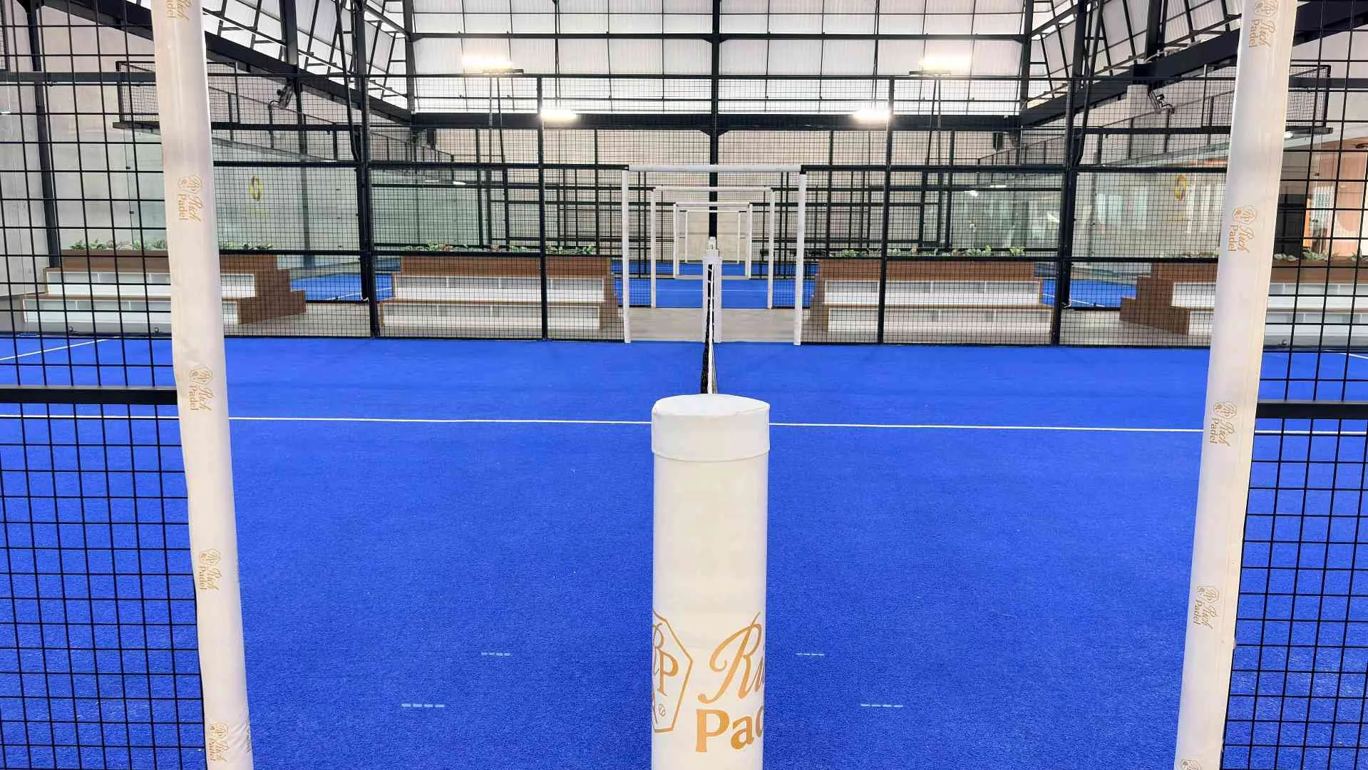 An indoor court at Rich Padel Sentul, the net post carrying the Rich Padel crest