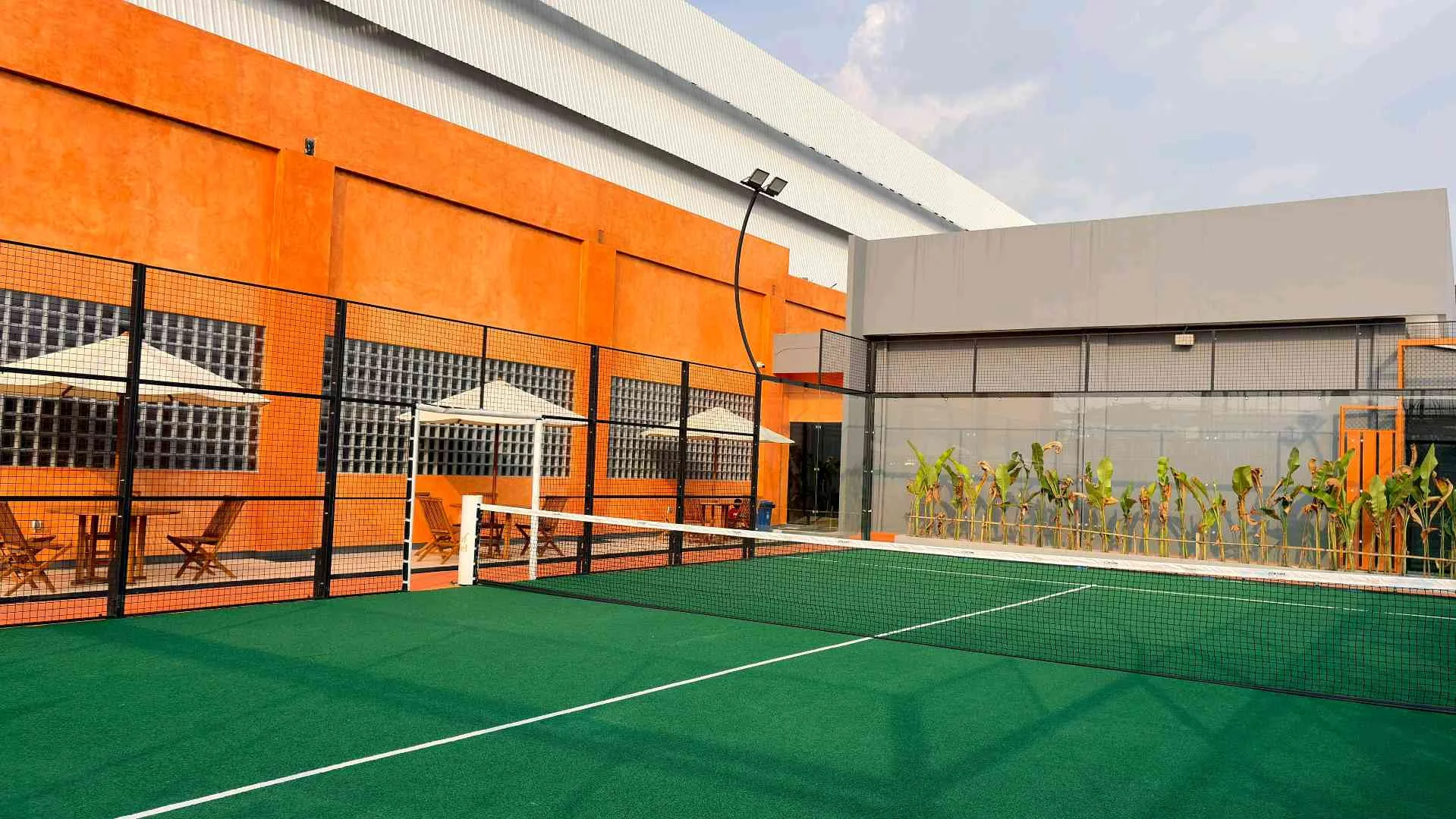 The outdoor court beside the building's burnt-orange wall and a terrace of parasols