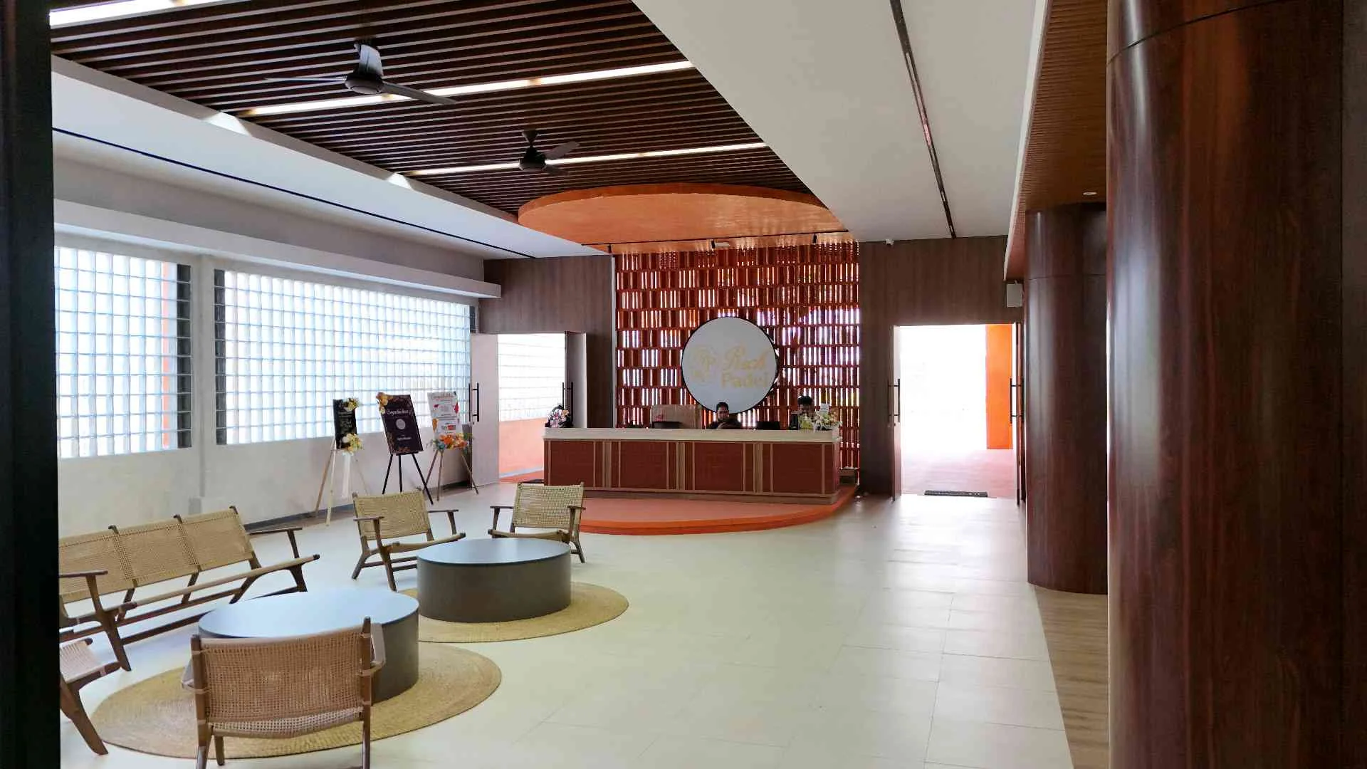 The reception lounge with a round mirror, armchairs and a terracotta feature wall